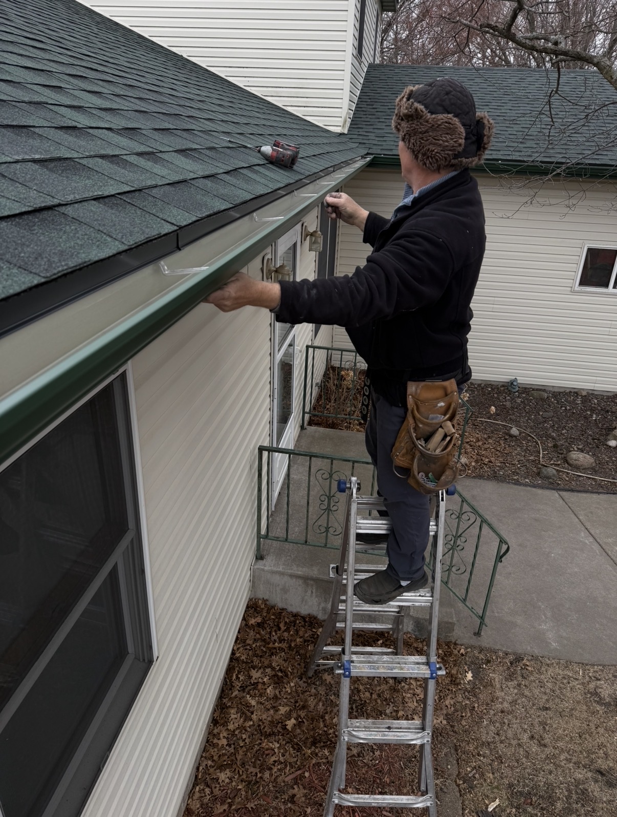 Anatoly Mustyatsa on a ladder hanging new gutters